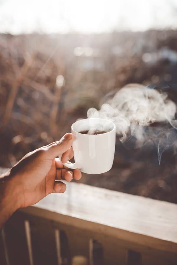 O cană de cafea aburindă în mână